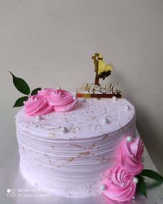 there is a white cake with pink flowers on the top and a gold name plate