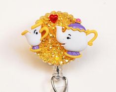 a couple of teapots that are sitting on a keychain with some sequins