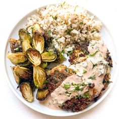 a white plate topped with meat, brussel sprouts and rice