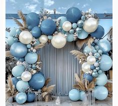 a blue and white balloon arch decorated with feathers, flowers and balloons for a wedding