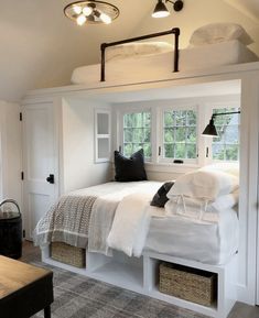 a bedroom with white bedding and lots of storage underneath the bed is shown in this image