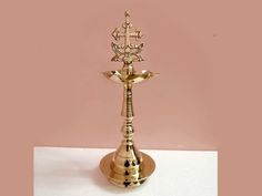 a gold colored candle holder on a pink background