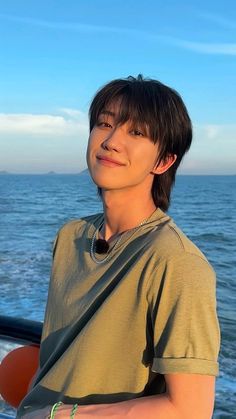 a young man standing on top of a boat near the ocean with his arms crossed