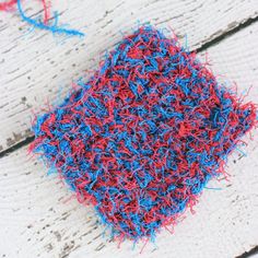 red, white and blue crocheted cloth on wooden planks with yarn sprinkles