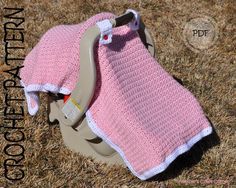 a crocheted pink and white blanket on top of a car seat in the grass