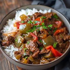 a bowl filled with beef and peppers on top of rice