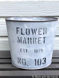 a flower market bucket sitting on the side of a building with no 103 written on it