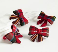 three red and green plaid bows on white napkins with one tied up to the side