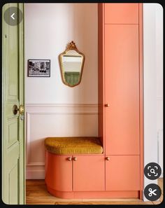 an orange bench in the corner of a room with a mirror on the wall above it