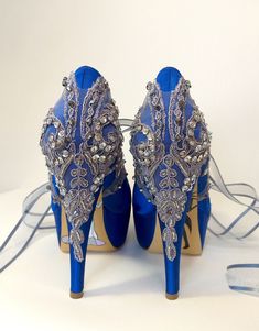 a pair of blue high heeled shoes sitting on top of a white table