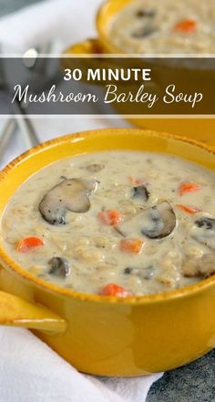 two yellow bowls filled with mushroom barley soup on top of a white table cloth next to spoons