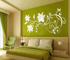 a bedroom decorated in green and pink with flowers painted on the wall above the bed