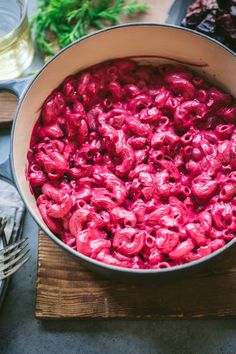 a pot filled with red food on top of a wooden cutting board