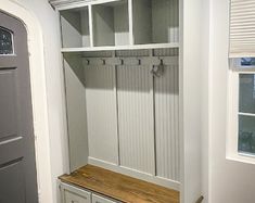 an empty white mudroom with wooden bench and storage cabinets on the wall next to it