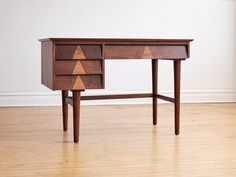 a wooden desk with two drawers on one side and an arrow design on the other