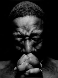 a black and white photo of a man with his hands folded in front of his face