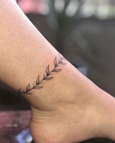 a woman's foot with a small branch tattoo on the left side of her leg