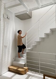 a man is climbing up the stairs in his house with white walls and metal railings