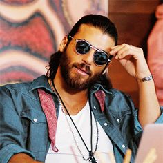 a man wearing sunglasses sitting in front of a laptop computer