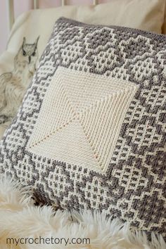 a crocheted pillow sitting on top of a bed