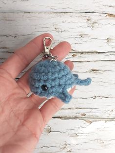 a hand holding a tiny blue crocheted animal keychain