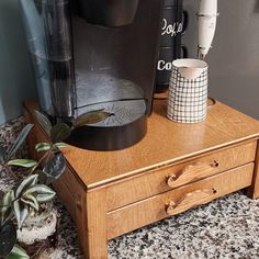 a coffee maker sitting on top of a wooden table next to a potted plant