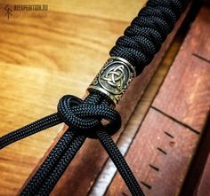 a close up of a black rope with a knot on it and a wooden box in the background