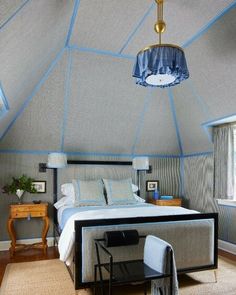 a bedroom with a bed, desk and chair under a blue skylight that is hanging from the ceiling