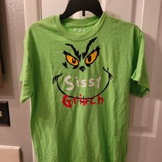 You're A Mean One, Mr. Grinch... You Really Are A Heel! But You Can't Deny There's Something Lovable About The Despicable Grinch. Show Your Christmas Spirit The Grinch Way. You Will Love Wearing This Classic T-Shirt To All Your Holiday Parties And Gatherings! This Green, Sz Medium Handmade T-Shirt Is On A Gildan 100% Cotton Shirt That States Sissy Grinch Color: Green Material: 100% Cotton The Grinch Christmas Tshirts, Grinchmas Tshirt, Georgia Bulldogs Shirt, Mr Grinch, Black Cat Lover, Bulldog Shirt, Green T Shirt, Trendy Graphic Tees, Coffee Shirts