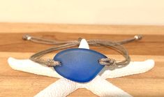 This sea glass bracelet is made from recycled glass and the glass is hand formed into a free form royal blue sea glass piece.. Each piece is slightly different in shape and measures about 1 inch. The bracelet is adjustable by pulling the end ties apart or together. It measures about 3.25 inches in diameter or 10 inches around when fully expanded and can be adjusted to fit any wrist It comes in a recycled box and is ready to be given as a gift. Perfect for beach lovers, surfers or anyone who love 4th Of July Recipes, Sea Glass Bracelet, July Recipes, Blue Sea Glass, Glass Bracelet, Wedding Bracelets, Beach Lovers, Wedding Bracelet, Recycled Glass