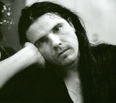 a black and white photo of a man with long hair