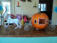 a horse drawn carriage sitting on top of a wooden table in front of a pumpkin