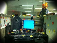 an office cubicle decorated for halloween with pumpkins, tombstones and computer screen