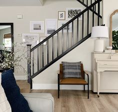 a living room filled with furniture and a stair case next to a white piano in front of a mirror