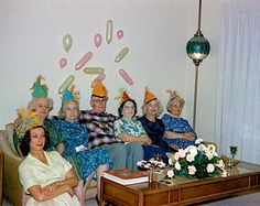 a group of people sitting on top of a couch wearing party hats with doughnuts drawn on the wall behind them