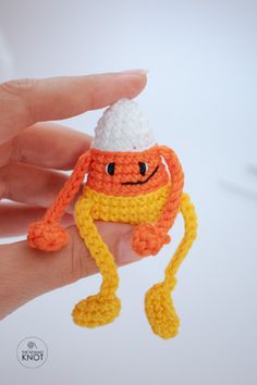 a hand holding a tiny crocheted orange and white hat