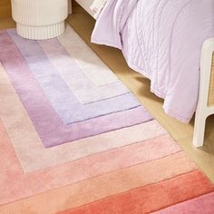 a bedroom with pink, purple and orange rugs on the floor next to a bed