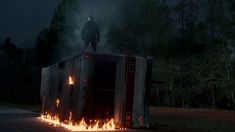 a man standing on the back of a truck with flames coming out of it at night