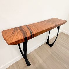 a wooden bench sitting on top of a hard wood floor next to a white wall