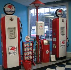 three old fashioned gas pumps are on display in a room with blue walls and black and white checkered flooring