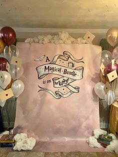 a pink backdrop with balloons and streamers in the shape of letters that read, a magic bundle is on the way