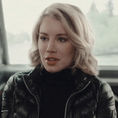 a woman with blonde hair and black jacket sitting in a car