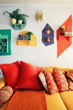 a living room filled with lots of furniture and colorful pillows on top of a yellow couch