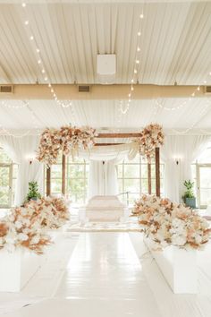 a wedding ceremony with white and pink flowers on the aisle, decorated with fairy lights