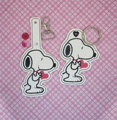 two keychains with cartoon characters on them sitting on a pink and white checkered tablecloth