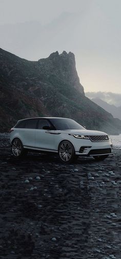 a white car parked on top of a rocky beach