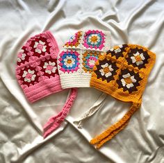 three crocheted hats laying on top of a white bed next to each other