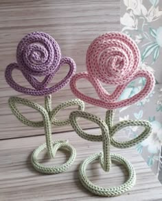 three crocheted roses sitting on top of a wooden table