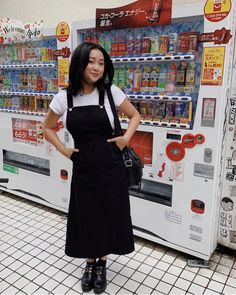 a woman standing in front of a vending machine with her hands on her hips