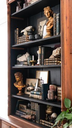 an antique bookcase with books, figurines and other decorative items on it